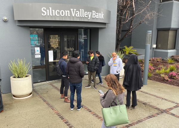 People stand outside a gray building that says "Silicon Valley Bank."
