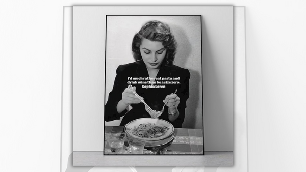 A black and white image shows a white woman eating pasta. On the image, white text says, "I'd much rather eat pasta and drink wine than be a size zero."
