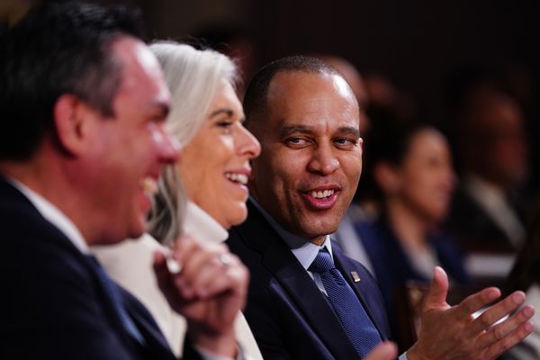 A Black man looks towards a white woman and Latino who are laughing next to him.