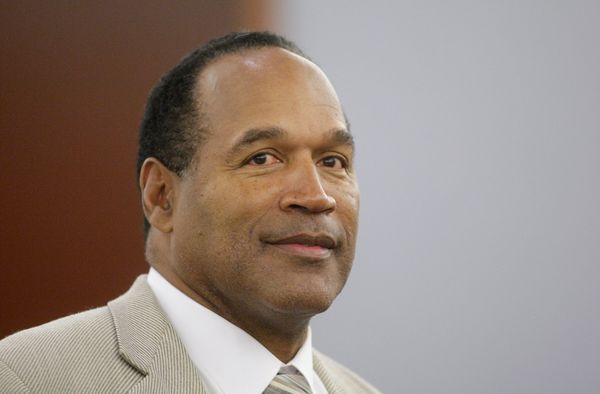 A Black man wearing a gray suit smiles.